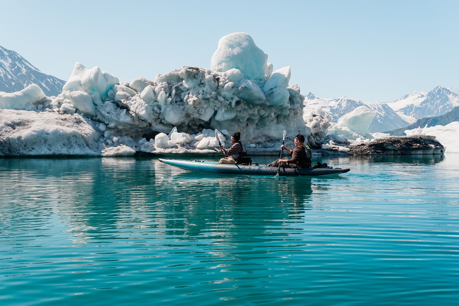 Couple kayaking in front of icebergs at Bear Glacier in Alaska.