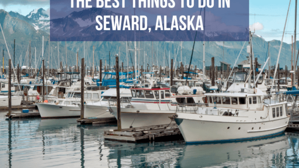 A scenic view of Seward Harbor with boats docked against a backdrop of mountains in Seward, Alaska.